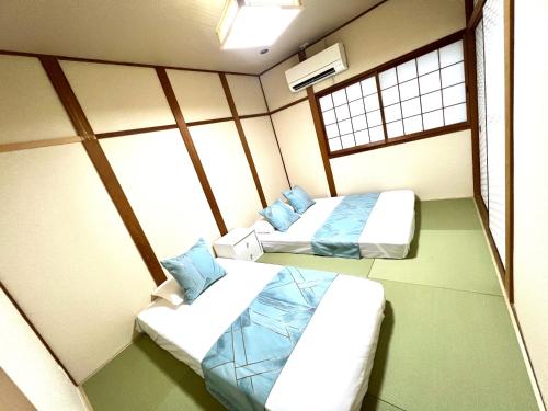 two beds in a room with two windows at 無料駐車場有!まるまる貸切!USjまで近く!海遊館!関西空港!西九条駅大阪駅直通!自転車4台利用可能 in Osaka