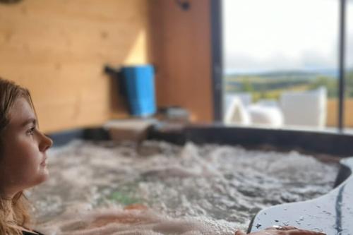 Une petite fille se baigne dans un bain à remous. dans l'établissement Chalet de Standing à Super Besse avec Jacuzzi SB2, à Besse-et-Saint-Anastaise