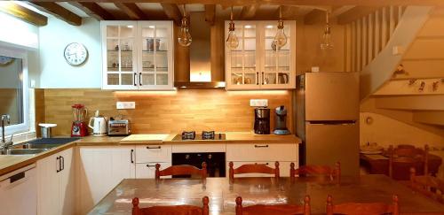 a kitchen with white cabinets and a table with chairs at Gîte Leomie - Maison en pierre au pied des vignes - Monthurel in Monthurel