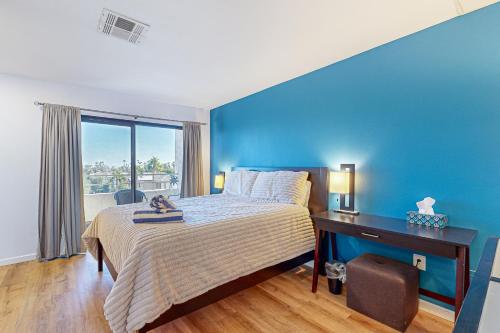 a bedroom with a blue wall and a bed and a desk at Biarrtx D20 in Palm Springs