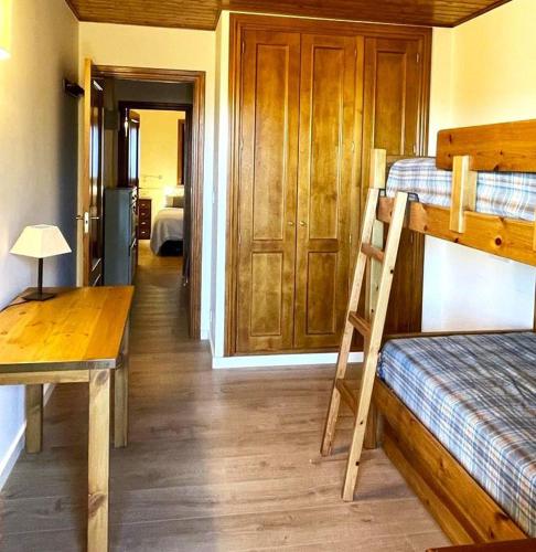 Cette chambre comprend 2 lits superposés, une table et un bureau. dans l'établissement Bonita planta baja con vistas panorámicas y piscina, à Enveitg