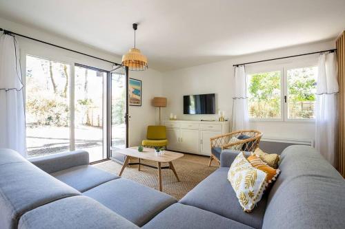 un salon avec un canapé bleu et une table dans l'établissement Villa Arbousière à deux pas de la plage PYLA SUR MER, à La Teste-de-Buch