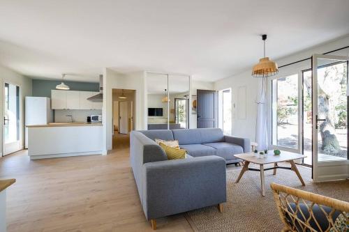un salon avec un canapé bleu et une table dans l'établissement Villa Arbousière à deux pas de la plage PYLA SUR MER, à La Teste-de-Buch