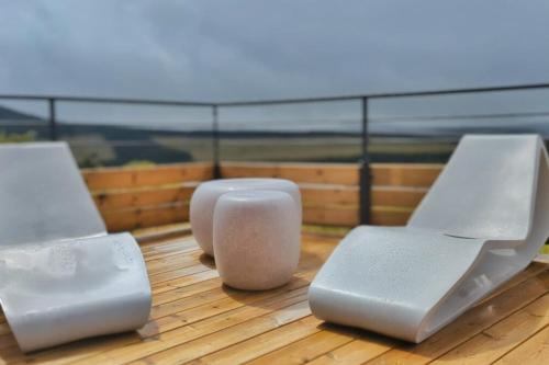 three white chairs sitting on top of a wooden floor at La Flèche 2 - Chalet Standing - Jacuzzi Privatif in Besse-et-Saint-Anastaise