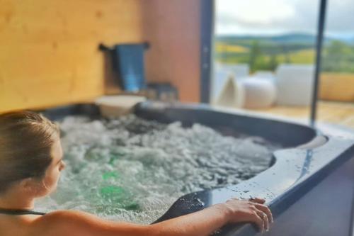 a woman in a bathtub filled with water at La Flèche 2 - Chalet Standing - Jacuzzi Privatif in Besse-et-Saint-Anastaise
