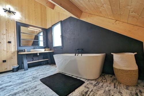 a large bathroom with a tub and a sink at La Flèche 2 - Chalet Standing - Jacuzzi Privatif in Besse-et-Saint-Anastaise