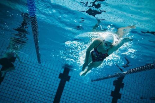 a woman swimming in the water in a pool at La Flèche 2 - Chalet Standing - Jacuzzi Privatif in Besse-et-Saint-Anastaise