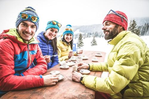 a group of people sitting at a table in the snow at La Flèche 2 - Chalet Standing - Jacuzzi Privatif in Besse-et-Saint-Anastaise