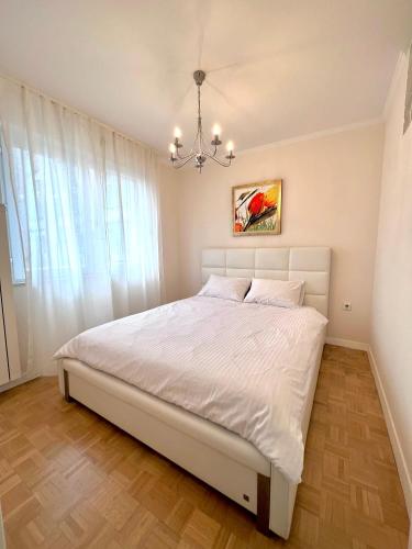 a bedroom with a white bed and a chandelier at Apartment Family in Zagreb