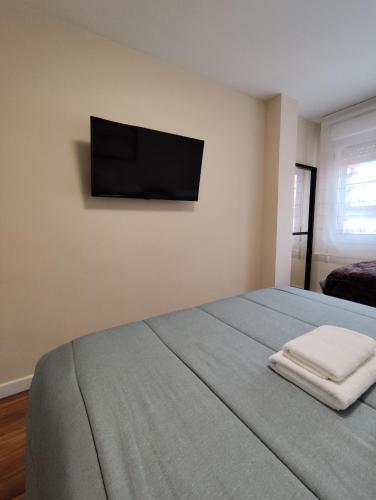 a bedroom with a bed with a flat screen tv on the wall at Piso recién reformado en Gascona in Oviedo