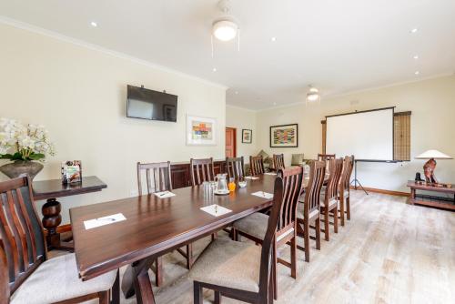 a conference room with a wooden table and chairs at Umthunzi Hotel and Conference in Umtentweni