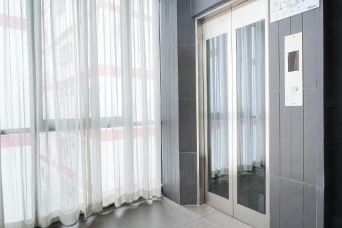 a room with large windows with curtains and a mirror at Marwin Space in Bangkok