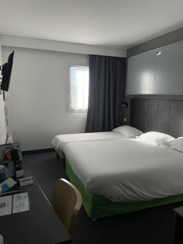 a hotel room with two beds and a window at Brit Hotel Marvejols in Marvejols