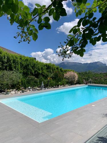 une piscine bleue avec une montagne en arrière-plan dans l'établissement Panorama Dream Annecy, Appart 42 m2 avec terrasse abritée, piscine et parking à 10 min d'Annecy, à Poisy