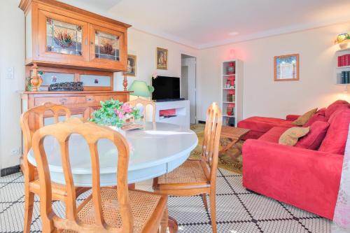 a living room with a table and chairs and a red couch at Gite cosy De Monplaisir in Périgueux