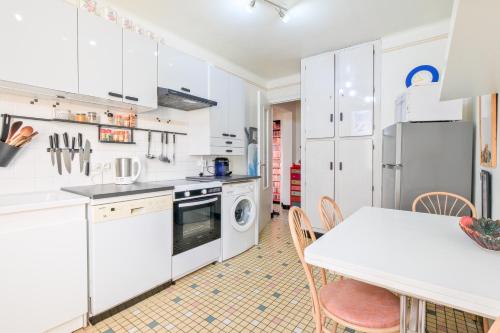a kitchen with white cabinets and a table and chairs at Gite cosy De Monplaisir in Périgueux