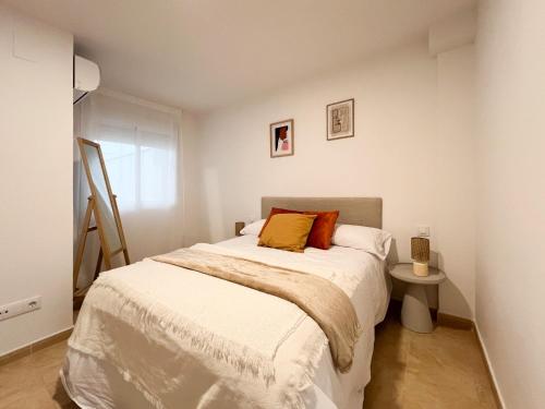 Un dormitorio con una cama con sábanas blancas y almohadas naranjas. en TAYP San Marcos 106, en Talayuela