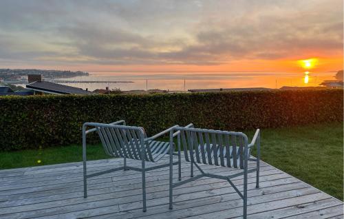 two benches sitting on a deck watching the sunset at 3 Bedroom Beautiful Home In Hejls in Hejls