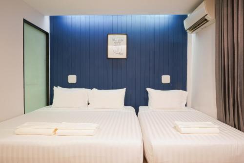 two beds in a room with a blue wall at Marwin Space in Bangkok