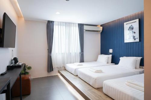 a hotel room with two beds and a television at Marwin Space in Bangkok
