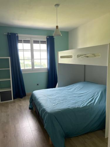 a bedroom with a bed with blue walls and a window at Les pieds dans la vallée in Châtillon-sur-Marne