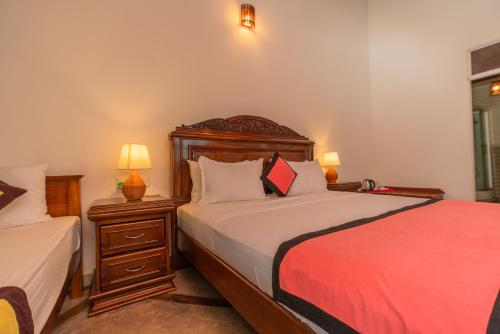 a bedroom with a bed and a night stand with two lamps at The Calm Of8 in Unawatuna