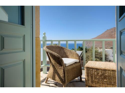 a wicker chair and a stool on a balcony at Santanna Suites in Patmos