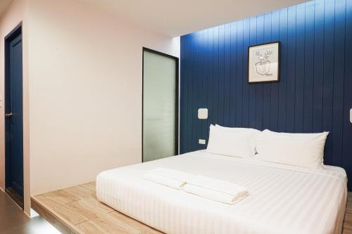 a bedroom with a white bed with a blue wall at Marwin Space in Bangkok