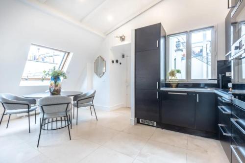 une cuisine avec des armoires noires et une table avec des chaises dans l'établissement Sweett - Boccador A, à Paris