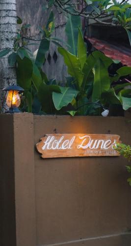a sign on top of a wooden sign on a wall at Dunes Unawatuna Hotel in Unawatuna