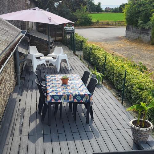 a table and chairs with an umbrella on a deck at Gîte des Lavandières in Amanlis