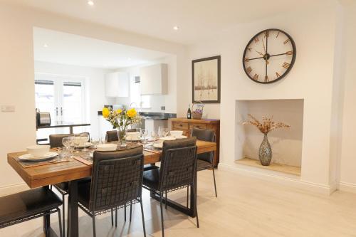 a dining room with a table and a clock on the wall at Apple Tree Corner - Harrogate in Harrogate