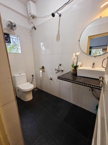 a bathroom with a toilet and a sink and a mirror at SOLS Backyard in Arambol