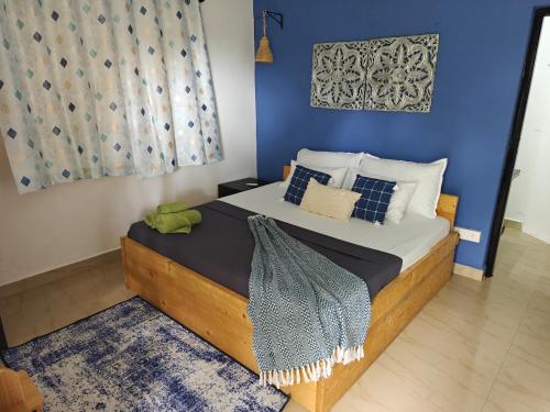 a bedroom with a bed with a blue wall at SOLS Backyard in Arambol