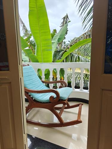 a rocking chair on a balcony with palm trees at SOLS Backyard in Arambol