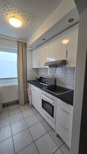 une cuisine avec des armoires blanches et un four à plaques de cuisson dans l'établissement guestified BEETHOVEN Serviced Apartments, à Ratingen