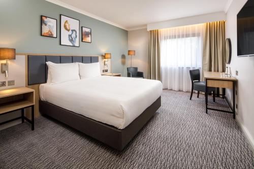 a hotel room with a large bed and a desk at Delta Hotels by Marriott Milton Keynes in Milton Keynes