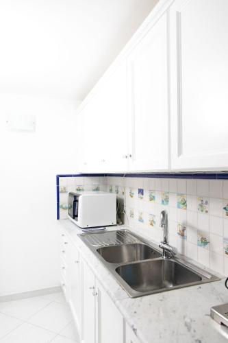 a white kitchen with a sink and a microwave at La Dolce Vita Ravello - Apartment with Balcony & Amazing View of the Amalfi Coast in Ravello