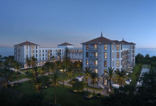 an aerial view of a building with palm trees and the ocean at Gran Hotel Taoro in Puerto de la Cruz