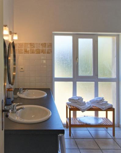 La salle de bains est pourvue de 2 lavabos et d'une grande fenêtre. dans l'établissement Domaine de Curé, à Conques-sur-Orbiel