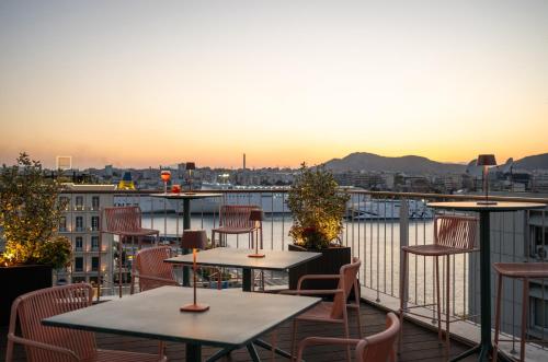 a patio with tables and chairs on a balcony at Mitsis N'U Piraeus Port in Piraeus