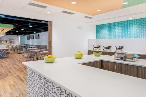 a large kitchen with white counter tops and tables at Beachside Hotel & Suites Cocoa Beach - Port Canaveral in Cocoa Beach