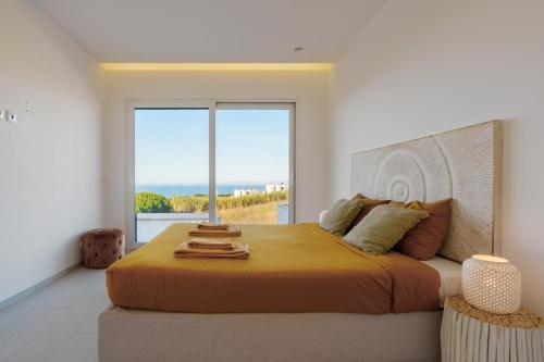 a bedroom with a large bed with a large window at Villa Beach and Friends with ocean view in Lourinhã