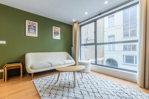 un salon avec un canapé et une grande fenêtre dans l'établissement Appart 2 chambres proche Vieux Lille, avec parking, à Lille