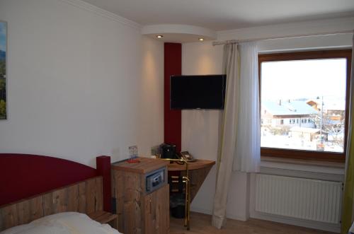Schlafzimmer mit einem Bett, einem TV und einem Fenster in der Unterkunft Alpchalet Schwanstein in Halblech