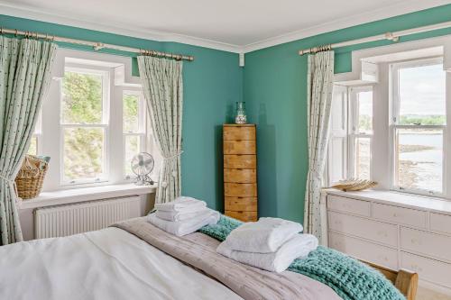 1 dormitorio con paredes azules y 1 cama con toallas en Balcary Tower, en Castle Douglas