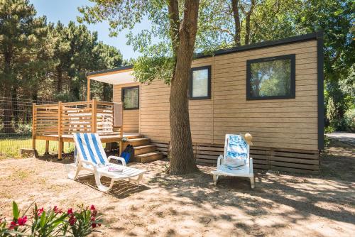 a tiny house with two chairs and a tree at Camping Le Méditerranée Argelès - Domaine piétonnier in Argelès-sur-Mer