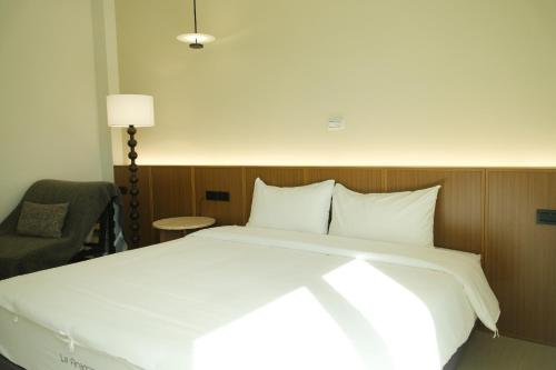 a bedroom with a large white bed and a chair at 蒔花澄旅 in Hengchun
