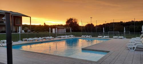 een zwembad met stoelen en een zonsondergang op de achtergrond bij Country Esmera in Desenzano del Garda
