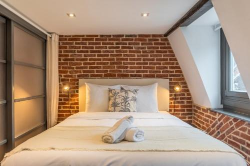 une chambre avec un lit avec un mur de briques dans l'établissement Two bedroom apartment in the heart of Old Lille, à Lille